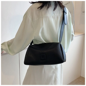 Detail of black pleated crossbody bag with matching leather tag and wide shoulder strap
