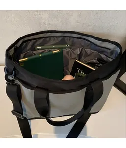 Interior view of spacious gray and black crossbody bag with books and electronics