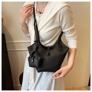 Detail of black pebbled leather bucket bag with curved rim and matching mini charm pouch