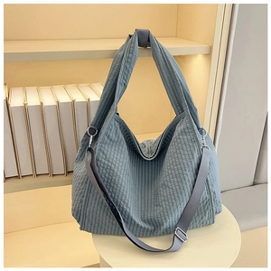 Detail of blue plaid canvas tote bag showing wide handle and adjustable crossbody strap