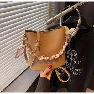 Detailed shot of brown litchi grain bucket bag with silk scarf handle and logo