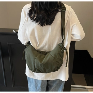 Detail of dark green crescent dumpling bag with pleated nylon fabric and adjustable strap