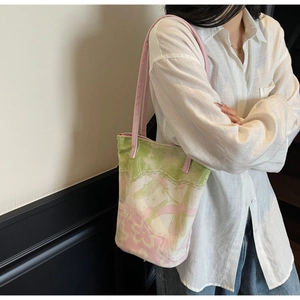 Detail of floral canvas tote bag with pink straps shown on a model in a minimalist setting