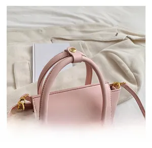 Detail of pink faux leather handbag with golden metal hardware and double top handles