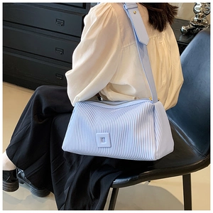Detail of light blue pleated shoulder bag with square buckle and wide strap on model