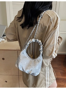 Silver crescent bag with rhinestone details and ruffled handle shown on model