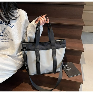 Close-up of large capacity tote bag featuring industrial buckle straps and wide shoulder strap