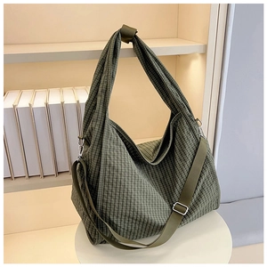 Detail of green checkered canvas tote bag with adjustable strap and metal hardware