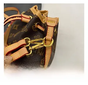 Close-up of golden metal hooks and drawstring detail on brown patterned bucket bag