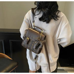 Detail of vintage brown bear monogram crossbody bag with gold hardware and charm