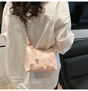 Détail du sac brodé rose avec appliques papillon 3D et pompons en perles blanches décoratives