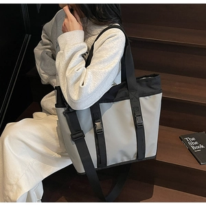Detail of grey canvas tote bag with black straps and adjustable plastic buckles
