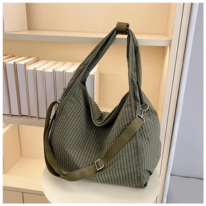 Close-up of green checkered canvas tote bag with adjustable strap and metal hardware