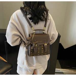Detailed view of the vintage brown teddy bear print backpack with a cute plush bear charm