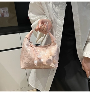 Détail d'un sac à main rose brodé avec des papillons en organza 3D et des perles