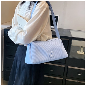 Close-up of light blue pleated shoulder bag with vertical stripes and wide strap