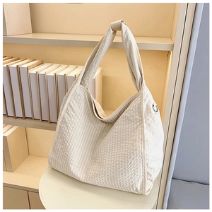 Detail of waffle textured canvas tote bag featuring a metal D-ring for charms