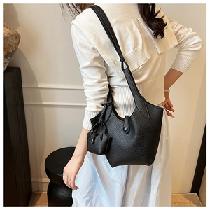 Detail of black lychee grain bucket bag featuring a detachable mini coin purse accessory