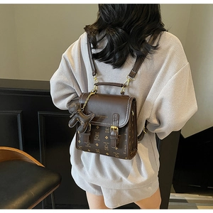 Detail of brown teddy bear pattern backpack with golden hardware and leather charm