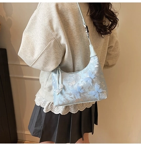 Detail of light blue crossbody bag featuring 3D butterfly embroidery and floral texture