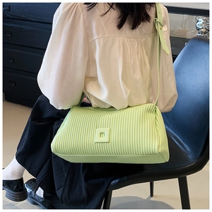 Detail of mint green pleated shoulder bag showing vertical textures and wide strap design