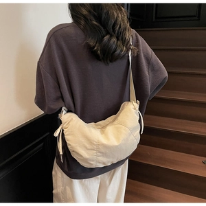 Minimalist beige dumpling crossbody bag featuring casual drawstring detail and wide strap