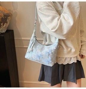 Détail du sac hobo bleu clair avec appliqués papillons 3D et broderies délicates