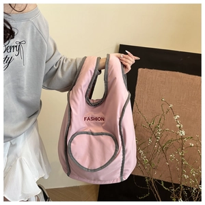Pink tote bag detail with heart-shaped pocket and red Fashion text on fabric