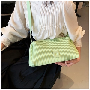 Close-up of light green pleated crossbody bag with matching shoulder strap on a model