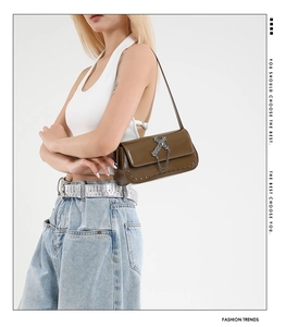 Detail view of brown vintage rivet shoulder bag with silver cross and chain hardware