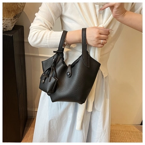 Detail of black pebbled leather bucket bag with matching mini charm and buckle closure