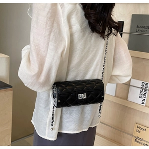 Close-up of elegant black quilted cylinder bag with silver chain and twist-lock