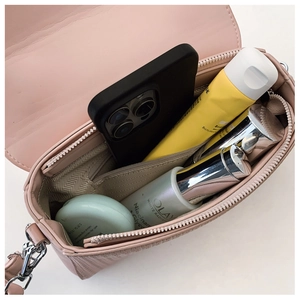 Detail view of pink crossbody bag interior with herringbone lining and daily essentials