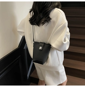 Chic black litchi leather bucket bag with silver metal lock shown on a model