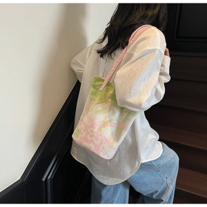 Detailed shoulder view of a large canvas tote bag featuring green floral art patterns