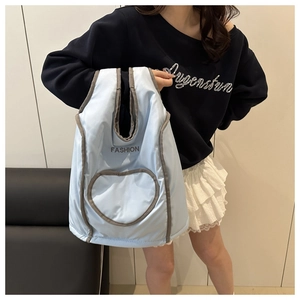 Close-up of quilted light blue puffy tote bag with heart-shaped pocket and fashion print