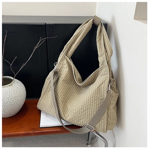 Detail of khaki checkered canvas tote bag with adjustable strap on a bench
