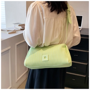 Detail of green pleated crossbody bag with square accent and adjustable strap