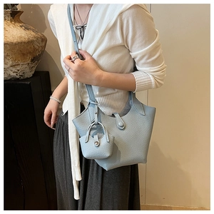 Detail of light blue bucket bag with lychee leather texture and mini pouch attachment