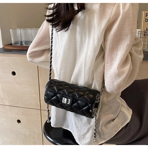 Detail of a black quilted leather cylinder bag with silver twist lock and chain strap