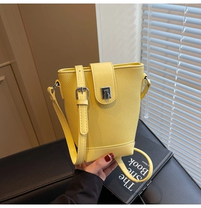 Detailed view of yellow bucket bag with lychee grain texture and silver metal clasp