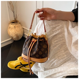 Detail of vintage bucket bag with monogram pattern, drawstring closure and gold hardware