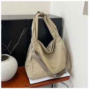 Detail of beige gingham canvas bag with textured fabric and adjustable strap on a bench