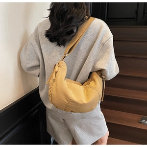 Detailed view of khaki nylon dumpling bag showing drape and texture on a model