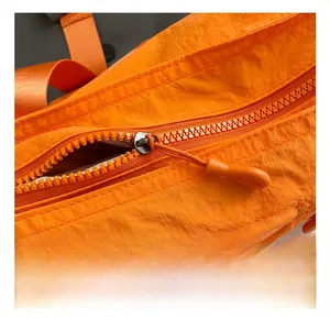 Detail of orange nylon fabric texture and high-quality metal zipper on crossbody bag