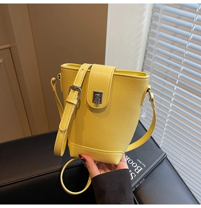 Detail view of yellow bucket bag with lychee texture and metallic silver buckle clasp
