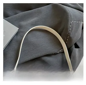 Detail of white leather shoulder strap and vintage black metal chain on a crossbody bag