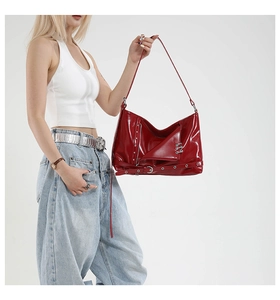 Detail of red patent leather tote bag with metal zippers and punk rivet studs