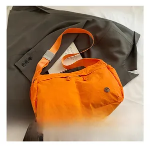 Detail view of bright orange nylon crossbody bag with dual drawstring pockets on a suit