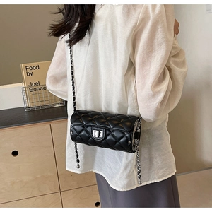 Close-up of black quilted cylinder crossbody bag with metallic turn-lock and chain strap